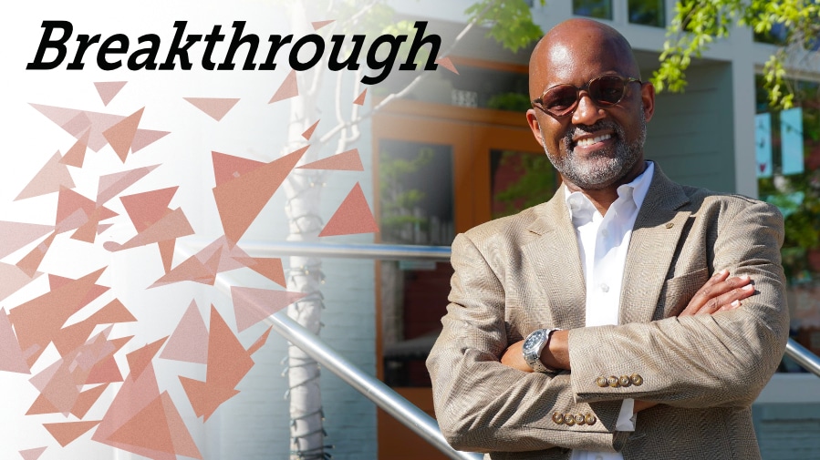A man stands in front of a building with the words breakthrough, representing God's restoration of Cornelius Williams and his work empowering urban leaders through DVULI principles.