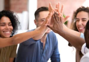 DVULI staff and facilitators attended workshops to enhance their understanding of key training modules, including asset-building and systems thinking. A group of people giving each other high fives.