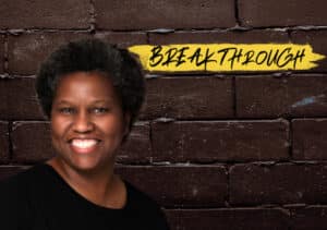 A smiling woman stands in front of a brick wall, representing Jennifer Jones' breakthrough in leadership through DVULI.