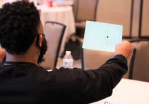 DVULI Second National Conference 2021: A man holding up a paper surrounded by motivated leaders striving for community youth development.