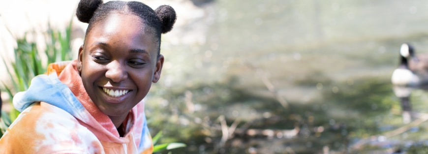 A young girl smiles in front of a duck, representing the empowerment of youth to make a difference with resources for urban communities.