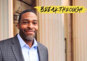 Jua Robinson, Director of Boston Collaborative, smiles in front of a city building, bringing redemptive change.