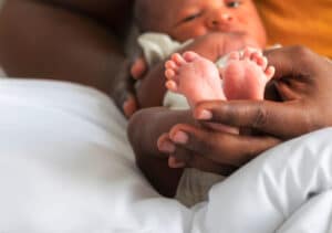 A woman holds a baby's feet, reminding youth of the vulnerable incarnation and Jesus' understanding of our human experience.