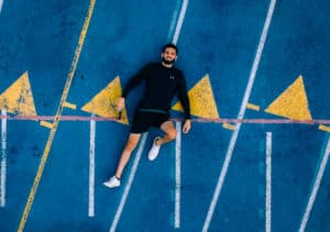 Image description: A man laying on a train track, representing the need for urban youth workers to slow down. From "Slow and Steady Wins the Race: Three Tips for Urban Youth Workers" by Jordan Francis (Phoenix 2018).